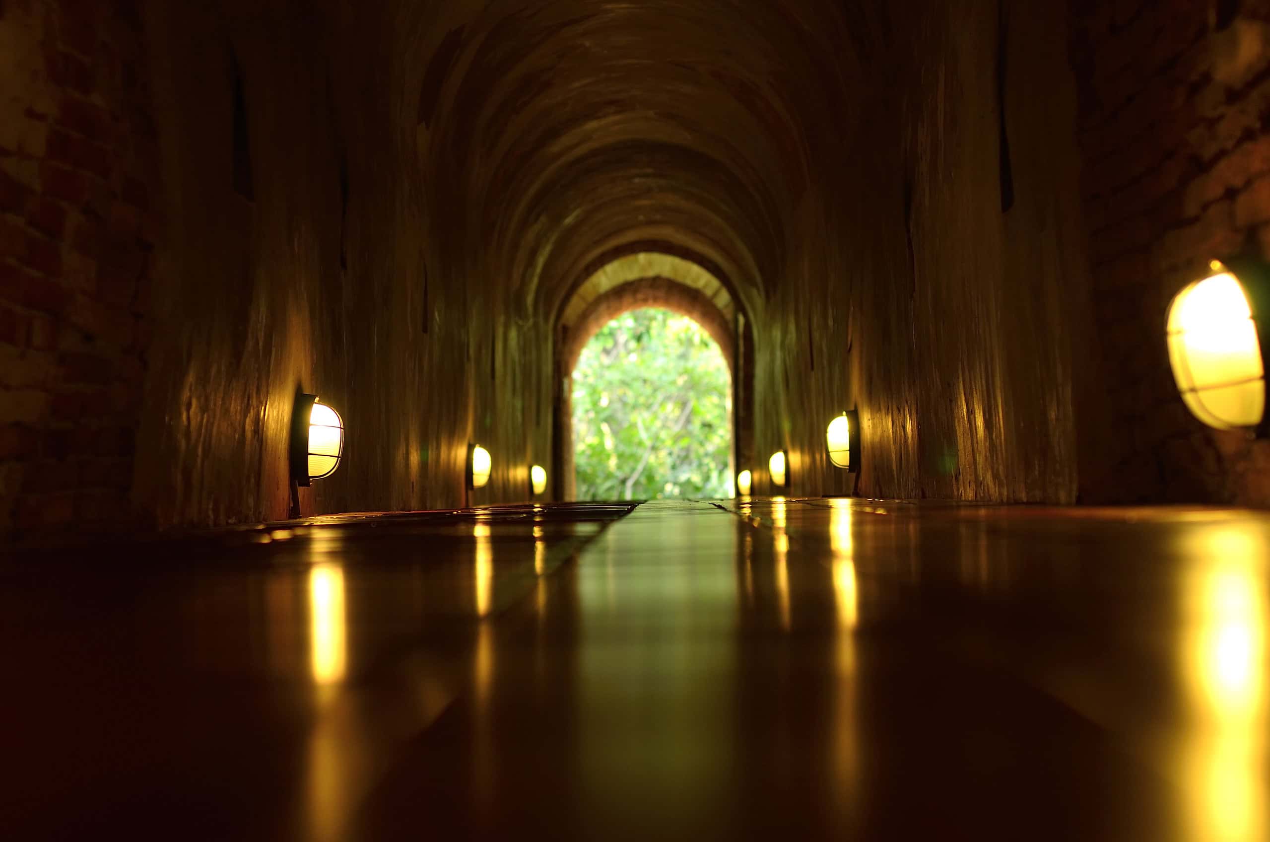 Fred i sjela, mørk og varm underjordisk tunnel med veggmonterte lys og utsikt mot grønt landskap. Perfekt sted for meditasjon, refleksjon og indre fred i naturens harmoni.